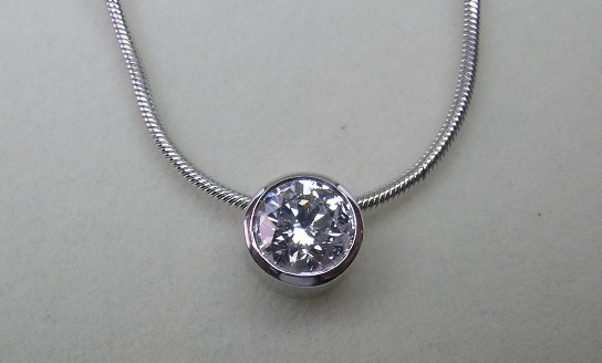 Delicate bezel set round brilliant cut diamond pendant and chain